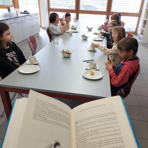 Kinder essen Zimtschnecken, trinken Kakao und hören eine Geschichte von Karlsson vom Dach von Astrid Lindgren